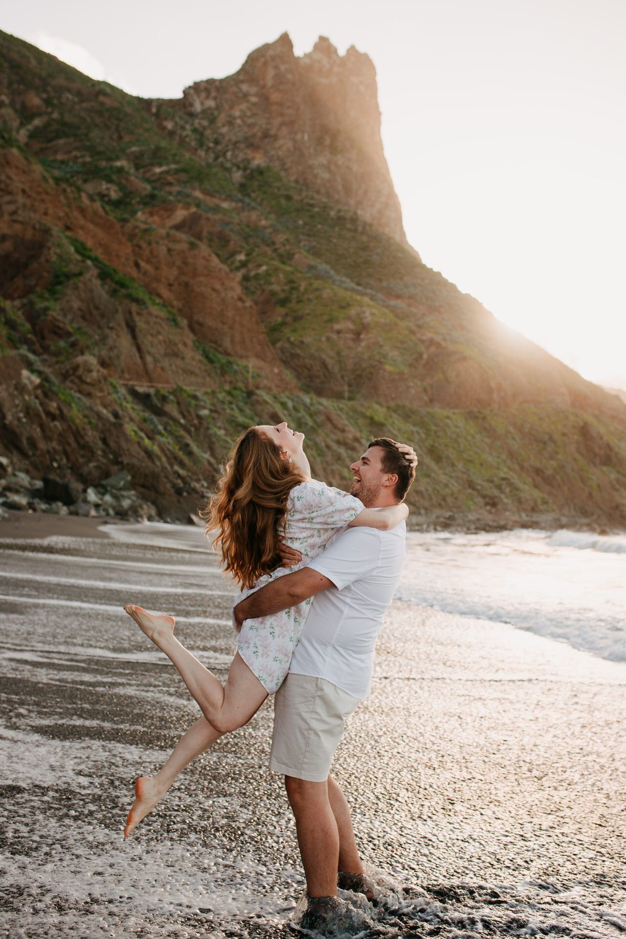 Photosession in Vienna a man is lifting his new fiancé at the beach in Tenerife, both are laughing